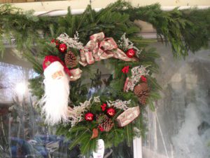 A wreath with santa clause and red ornaments.