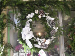 A wreath of pine needles, white flowers and other decorations.