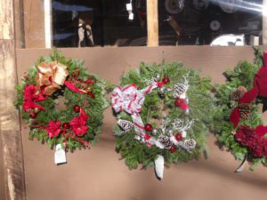 Three wreaths hanging on a wall with ribbons.