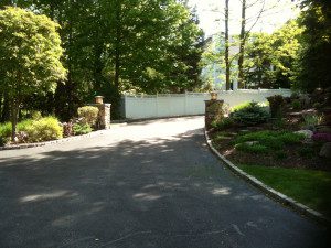 Driveway leading to white gate and garden.