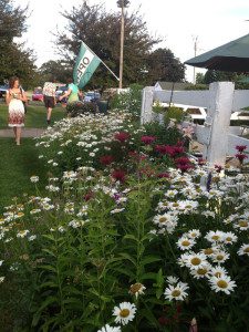 A woman walking in front of some flowers