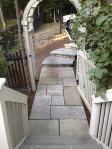 A walkway with steps leading to the side of a house.