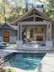 Outdoor patio with pool and stone fireplace.