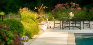 A patio with benches and flowers in the background.