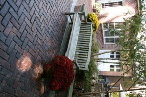Wooden bench with flowers on brick patio.