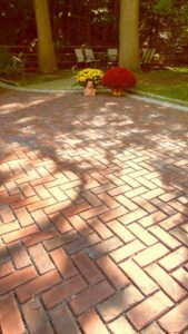A brick driveway with flowers in the middle of it.