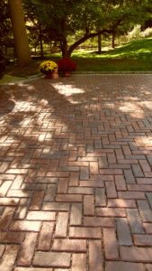 A brick driveway with a basket of flowers in the middle.