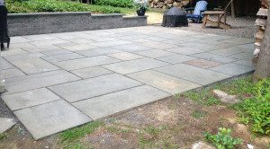 A patio with a fire pit and stone wall.