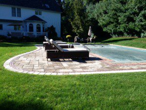 A pool with a lawn chair and umbrella.