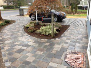 Stone driveway with car and mailbox.