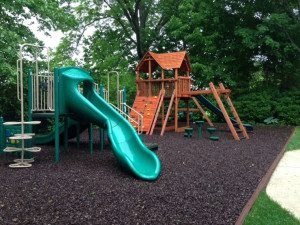 A playground with slides and swings in the middle of a park.