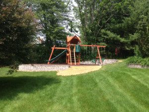 A wooden swing set in the middle of a yard.